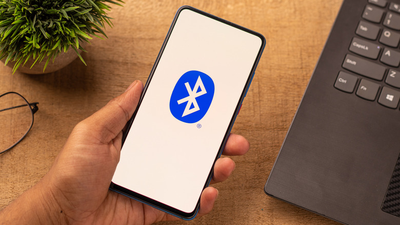 A hand holding a phone with a large Bluetooth logo on it