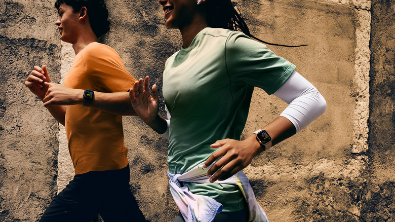Two people running, both with an Apple Watch SE 3 on their wrist.