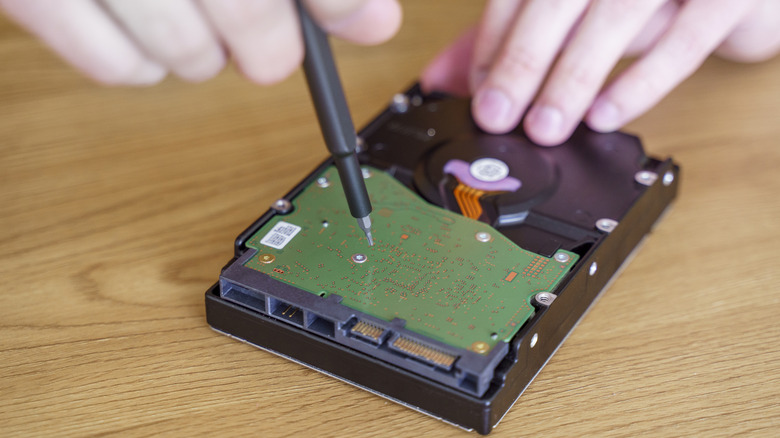 A person using a precision screwdriver to repair a computer hard drive.