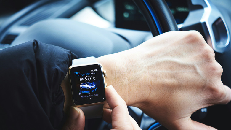 Closeup of a person fiddling with their Apple Watch while behind the wheel