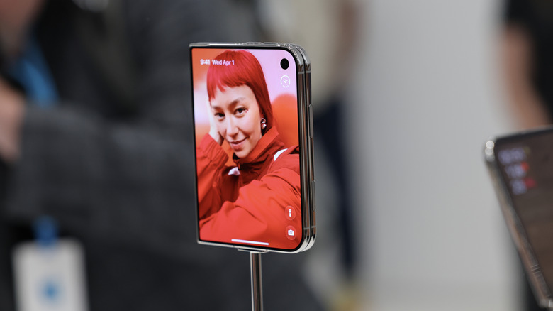 The iPhone Duo's outer display showing a person on the wallpaper, plus various controls.