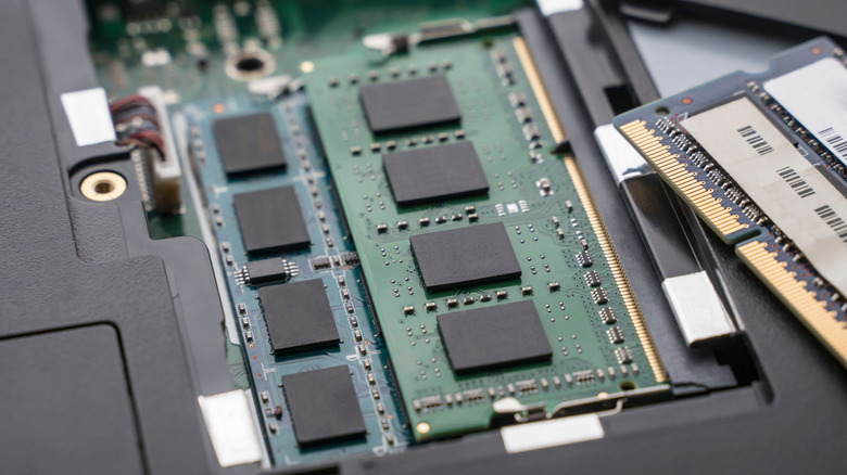 RAM sticks inside a laptop, with another stick nearby.