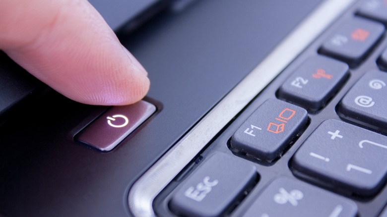 Close-up of a finger on a laptop's power button.