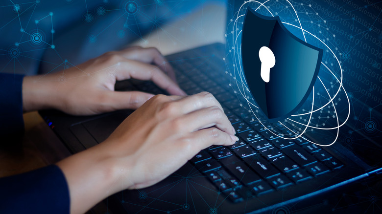 Hands typing on a laptop with a shield and keyhole above it.