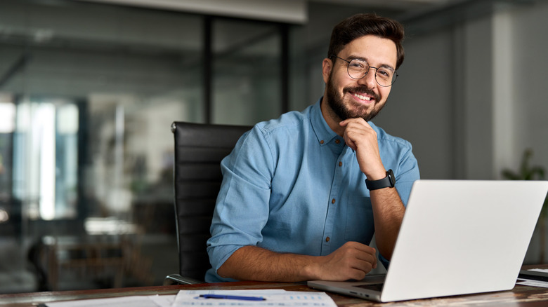 A man looking happy while working at his laptop.