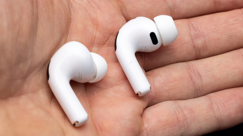 A pair of AirPod Pro earbuds out of their case and held in the palm of someone's hand.