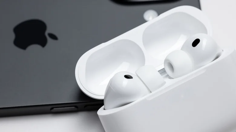 An iPhone next to AirPods with the charging case lid open.