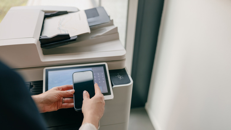 A person using a smartphone to operate a printer.