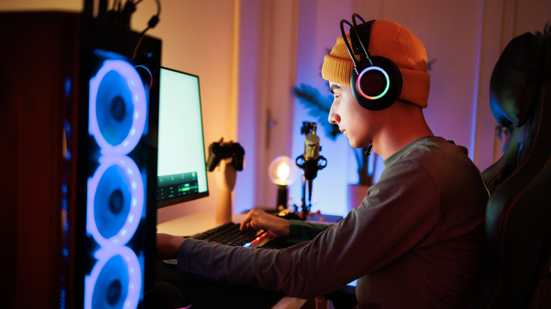 A person sitting at a lit-up desktop PC while wearing RGB headphones.
