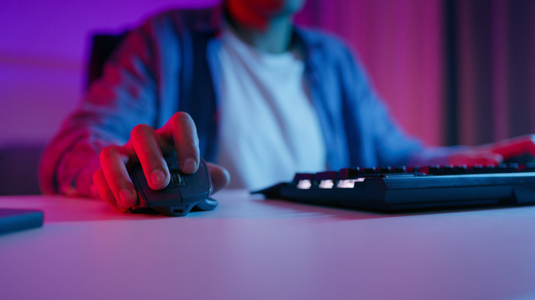 Someone sitting at a computer utilizing a wireless mouse