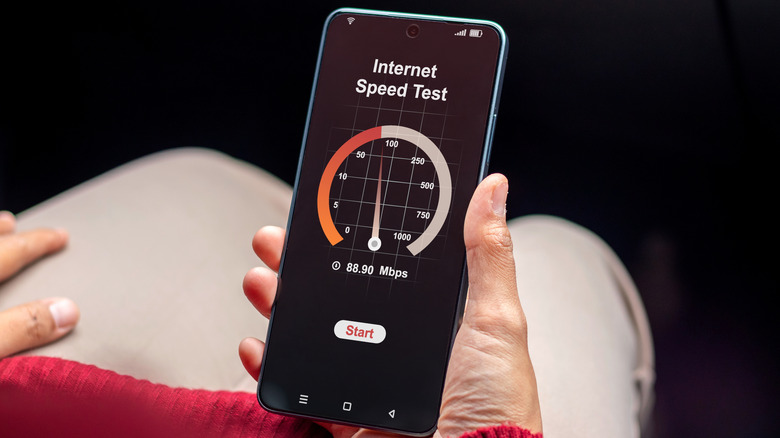 A person holds a smartphone displaying an internet speed test.