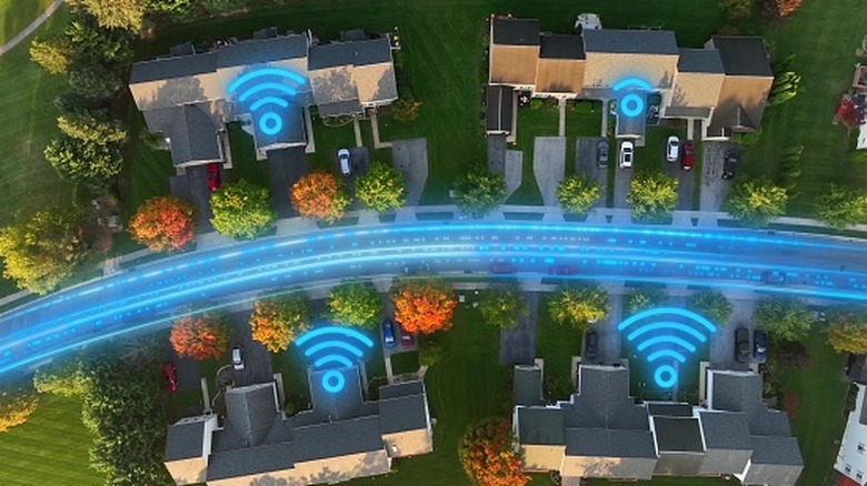 Aerial view of a residential neighborhood with glowing wireless icons over several homes and a blue network graphic running along the street.