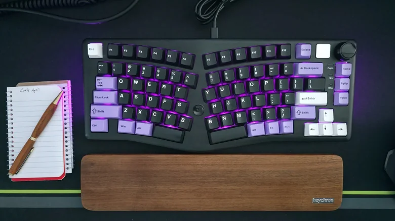 LeoBog Alice A75 split-layout ergonomic mechanical keyboard on desk with Keychron wristpad, a pen and spiral notebook.