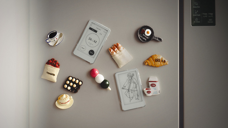 Photo of two Boox Pico ereaders stuck to a stainless steel refrigerator alongside several small magnets of food items, including an espresso, dango, and a croissant.