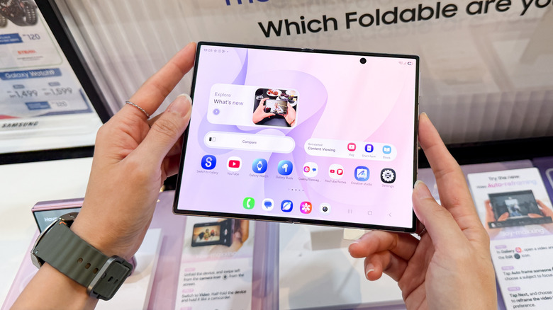 A person holding an unfolded Z Fold 8 displaying the home screen.