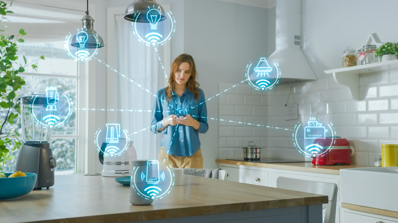 Woman using a smartphone in a kitchen with connected smart-home devices shown over Wi-Fi.
