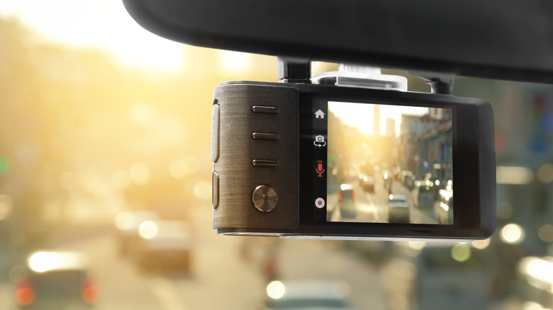 Close-up of a dash cam mounted to the bottom of a car's rearview mirror.