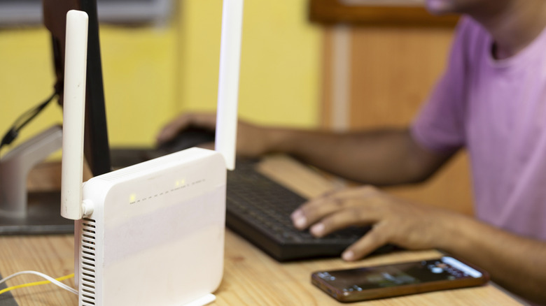 Wi-Fi router on desk alongside keyboard and smartphone.