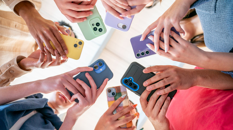A group of young people in a circle using their phones