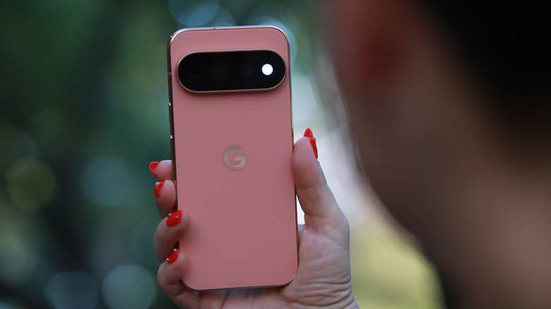 A pink Google Pixel 11 Pro being held, showing the back side with the camera.