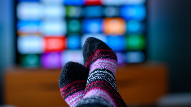 Fuzzy pink and black socks with a blurred TV in the background.