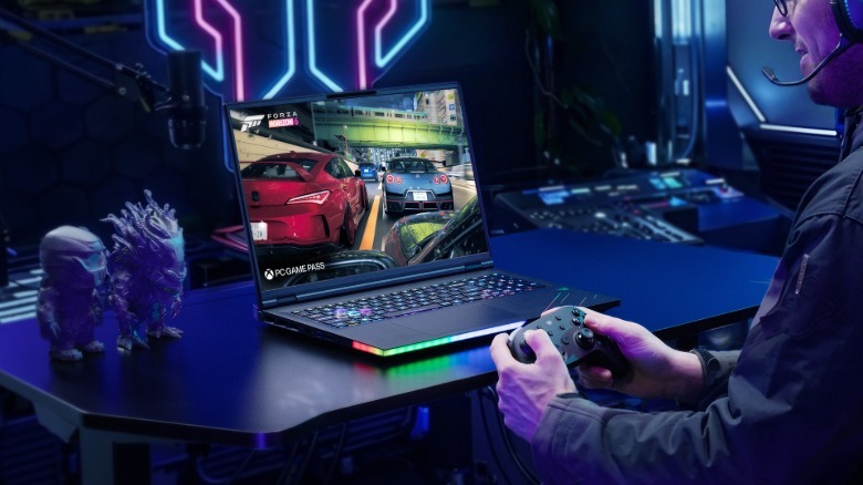 Lifestyle photo of an Acer Predator Helios 18 AI laptop on a desk as man holds a controller