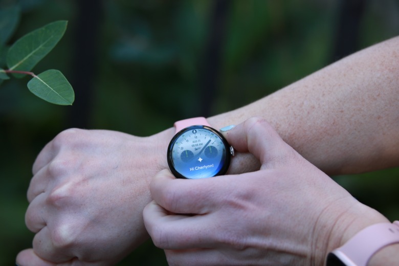 A person pressing the button on the Pixel Watch 5 with its screen showing the new Gemini pop-up.
