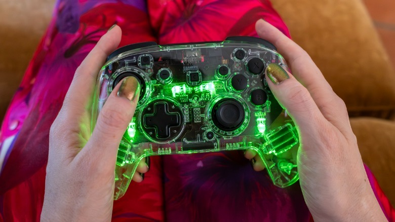 Afterglow controller glowing green against pink floral pants.