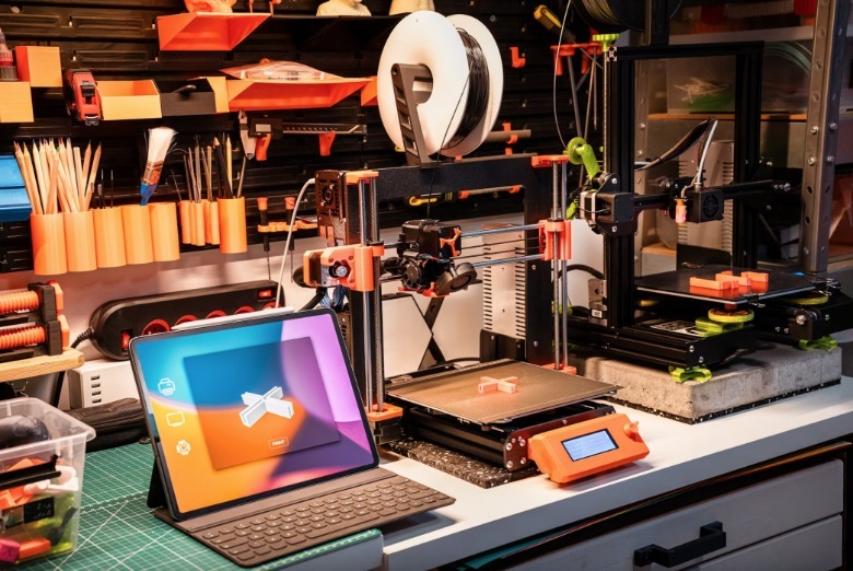 A 3D printer station with a laptop and many tools.