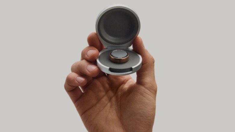 A hand holding up a smart ring.