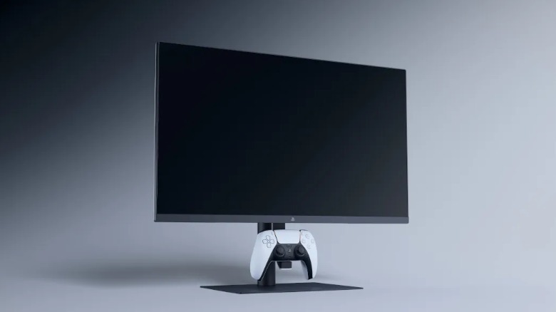 A monitor with a DualSense controller resting on a hook underneath the screen