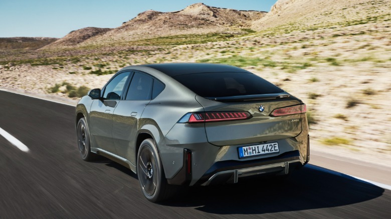 BMW iX4 M50 xDrive shown in grey from the rear on a desert road