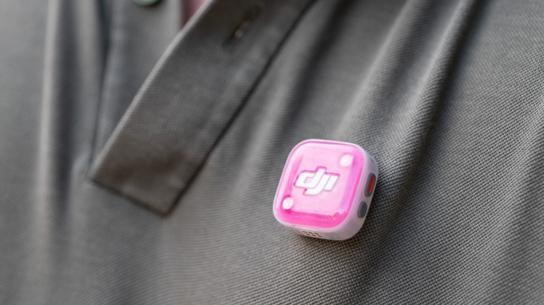 DJI's Mic Mini 2S transmitter is shown with a pink cover on a brown shirt