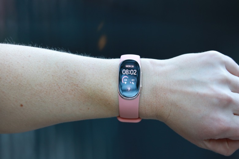 A Fitbit Edge with pink silicone band on a person's wrist.