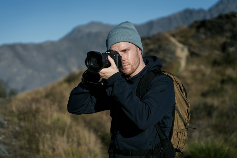 Photographer using Sony A7R VI camera in mountainous environment