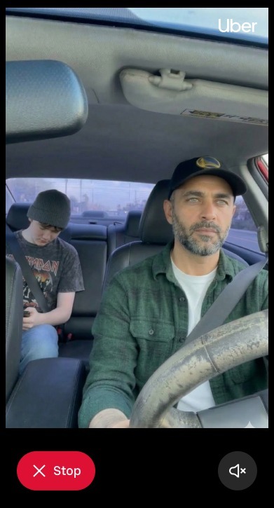 A phone screenshot featureing an image of a driver and young passenger in the rear seat with an Uber watermark in the top right. There are Stop and Mute buttons at the bottom.